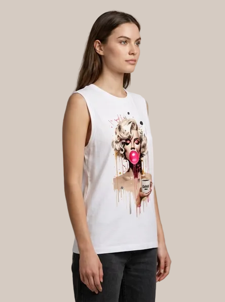 A woman modeling a white sleeveless muscle tank top with a colorful graphic print of Marilyn Monroe holding a pink heart-shaped object, paired with dark jeans against a neutral studio background.