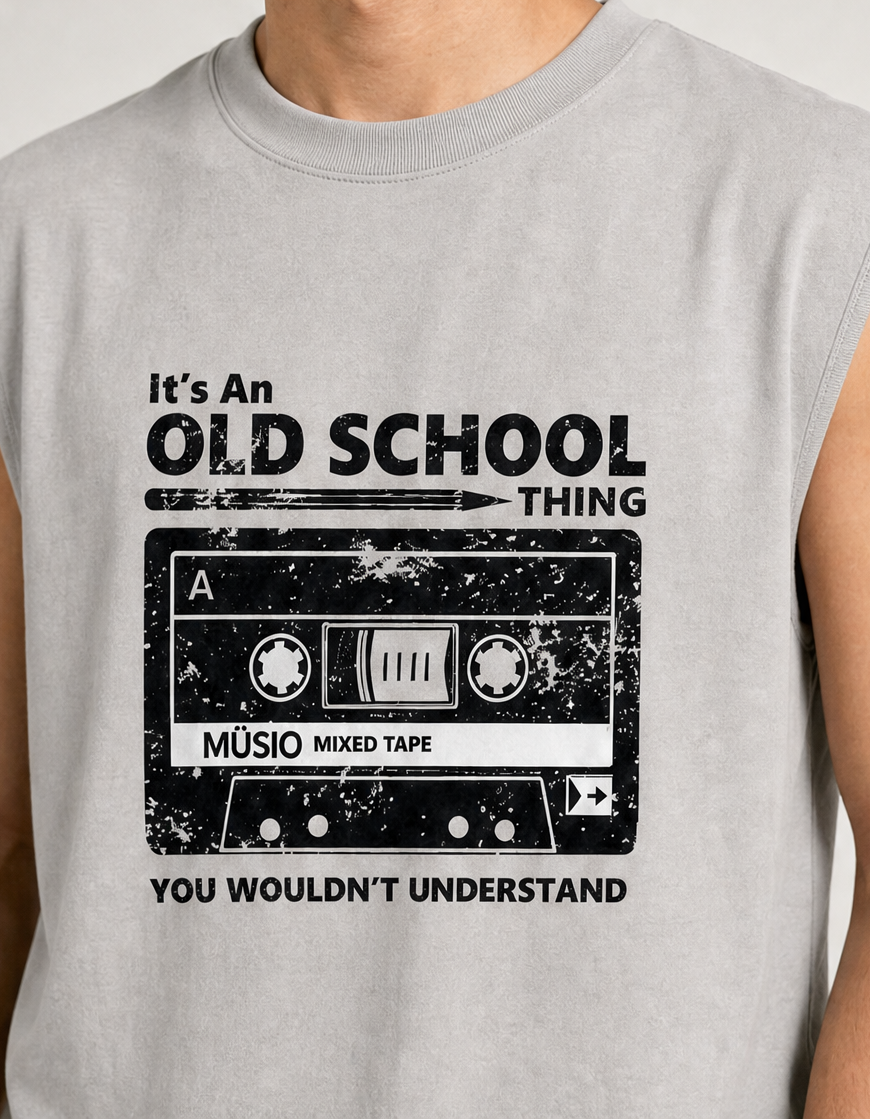A close-up of a person wearing a light gray sleeveless muscle t-shirt with a distressed black graphic of a cassette tape and the text 'It's An OLD SCHOOL THING YOU WOULDN'T UNDERSTAND'.