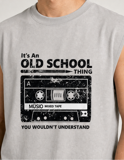 A close-up of a person wearing a light gray sleeveless muscle t-shirt with a distressed black graphic of a cassette tape and the text 'It's An OLD SCHOOL THING YOU WOULDN'T UNDERSTAND'.
