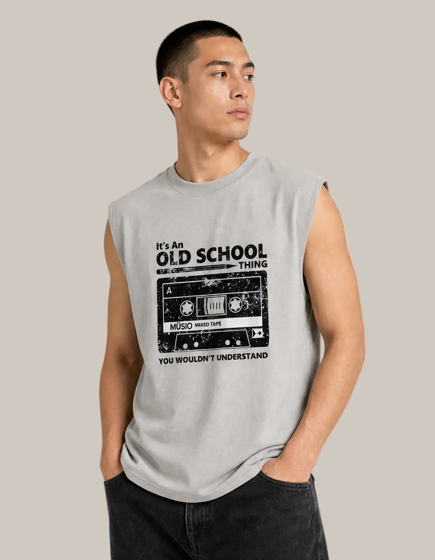 A man wearing a light gray sleeveless muscle t-shirt with a black graphic of a cassette tape and the text 'It's An OLD SCHOOL THING YOU wouldn't understand'.