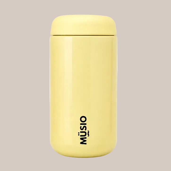A pale yellow insulated water bottle with a matching lid, featuring the black vertical 'MÜSIO' logo near the bottom, set against a plain white background.